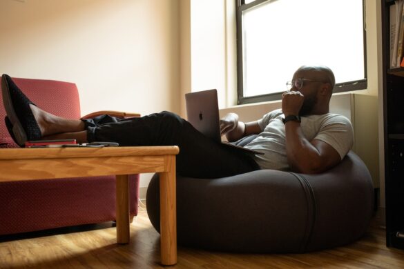 Black man working from home sitting on a beanbag.