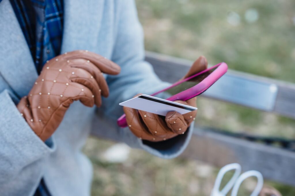 Woman in gloves making online purchase on her phone.