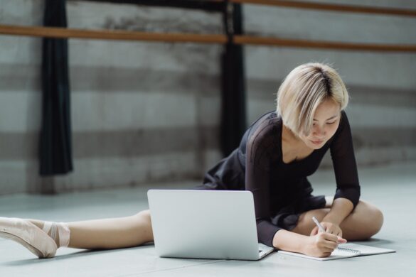 Woman ballerina stretching and working on computer