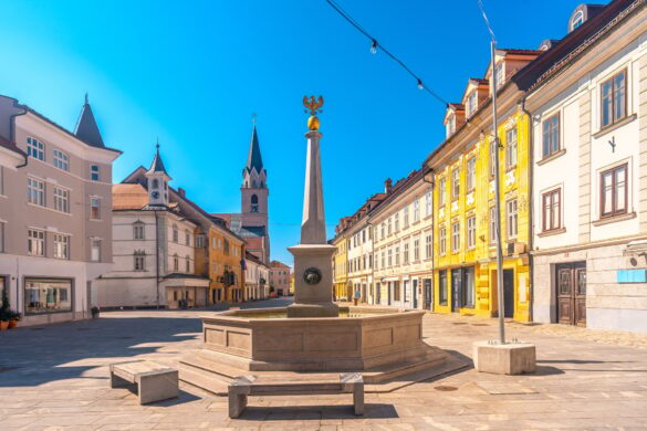 Fountain and parish church of saint kancijan illuminating kranj main square in summer