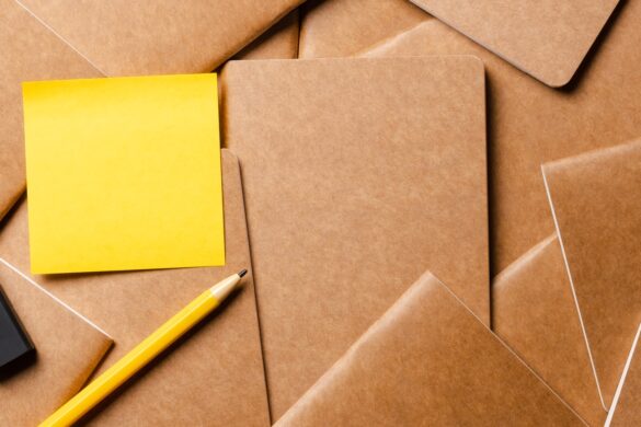 yellow sticky note on kraft brown notebook on table
