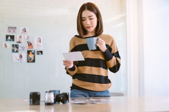 Freelancer Korean or Japanese female drinking coffee and checking the best images from photoshoot.